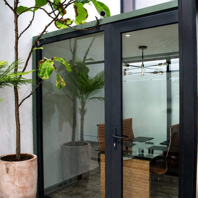 Oficina privada de Grou Co con vidrio, vegetación y luz natural